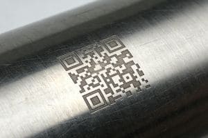 Fiber laser engraved QR code on a cylindrical stainless steel surface for industrial parts traceability.