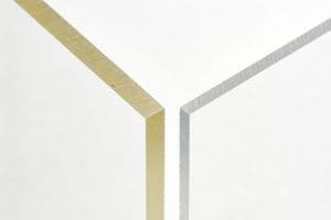 A side-by-side comparison of laser-cut polycarbonate sheets showing a yellowed edge on the left and a clean, clear edge on the right.