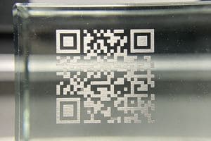 A high-contrast QR code marked on a transparent glass substrate using a UV laser, showing precision without structural cracking.